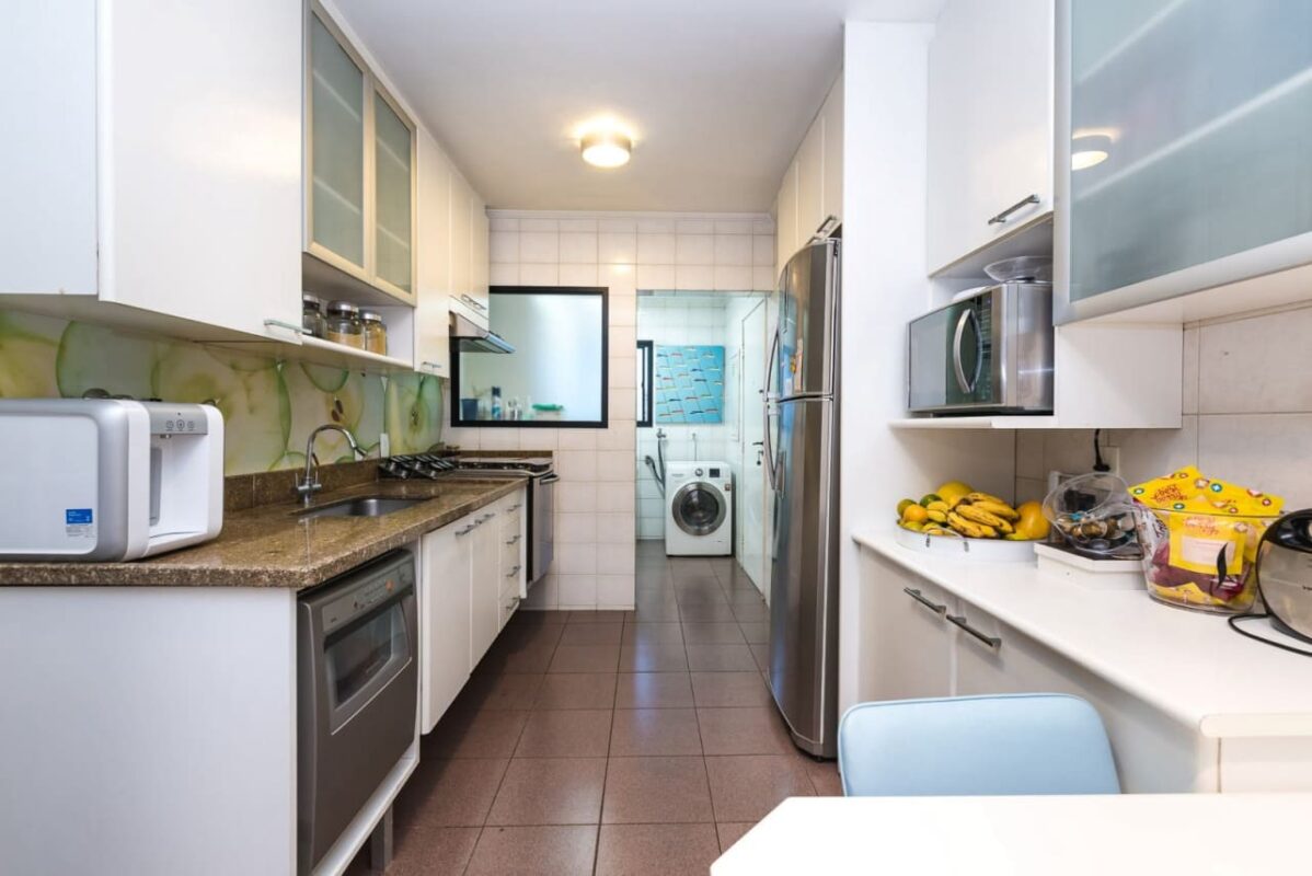 Cozinha organizada com móveis brancos e eletrodomésticos modernos