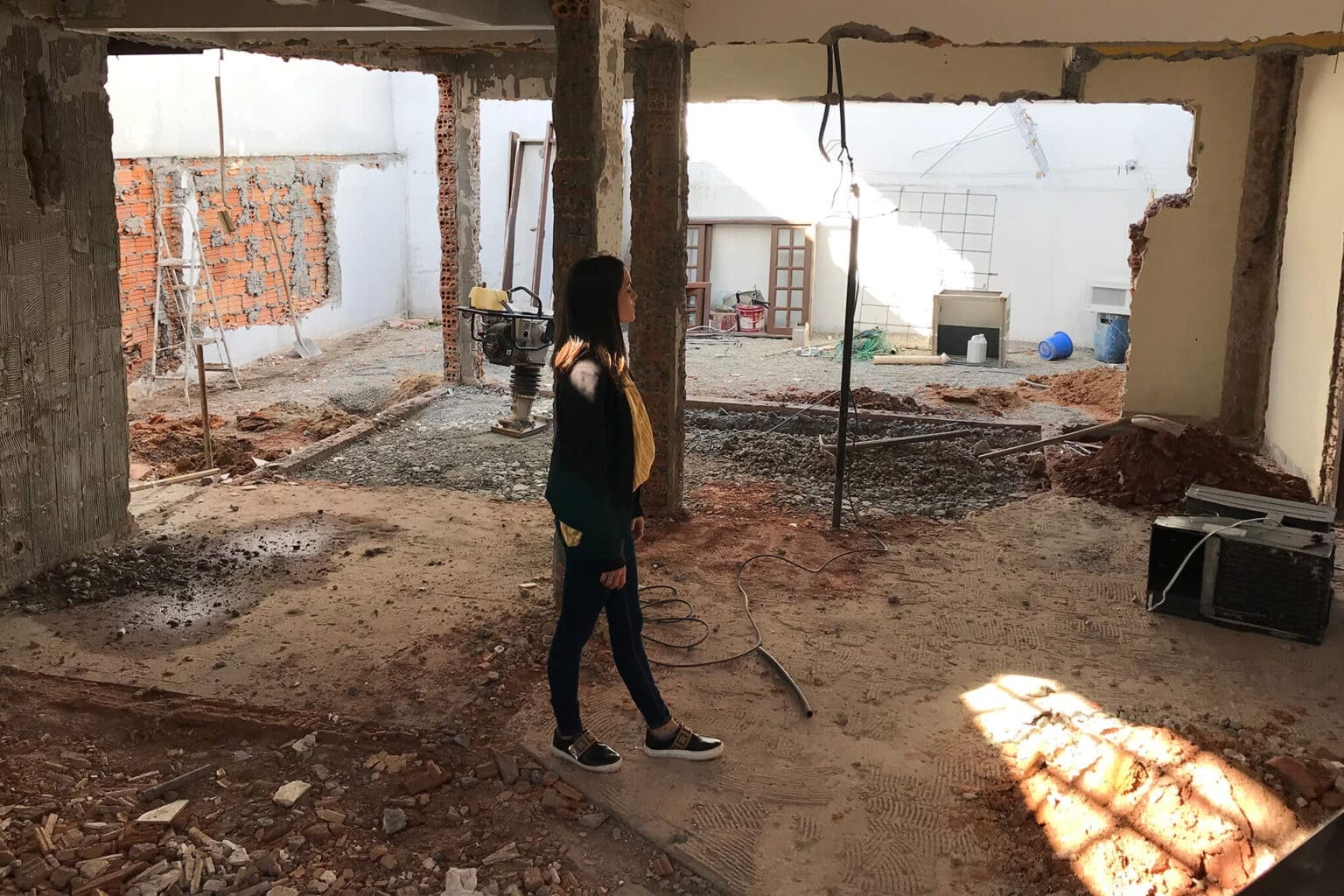 Mulher parada em meio a reforma de um imóvel