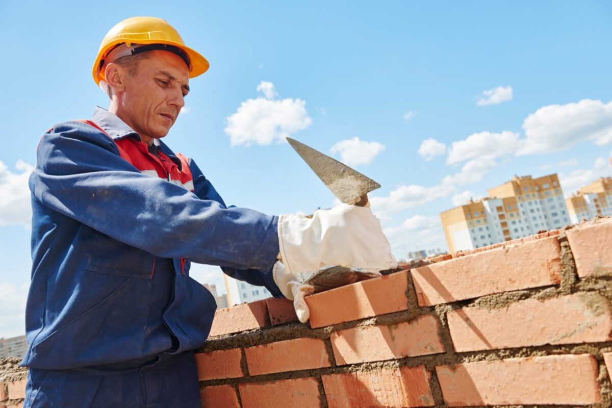 Pedreiro colocando cimento nos tijolos em uma obra